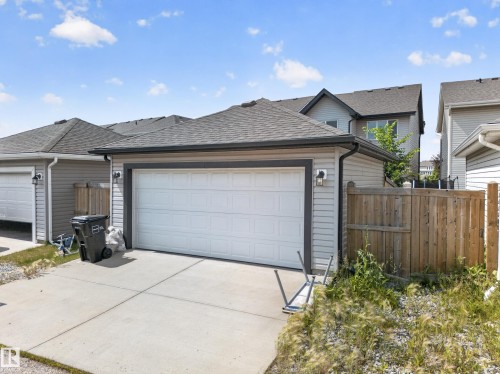 Detached garage with horizontal siding, a white overhead door, and a concrete driveway - 227 Cy Becker Blvd, Edmonton, AB 