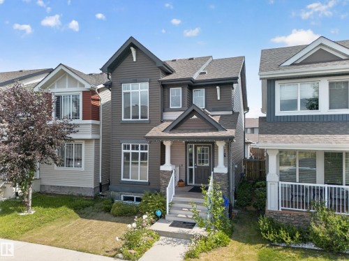 Two-story residence featuring a dark-toned facade with white trim accents and multiple window configurations - 227 Cy Becker Blvd, Edmonton, AB 