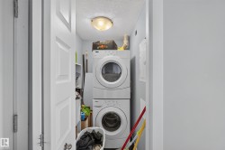 Dedicated laundry area featuring a stacked washer and dryer unit, overhead flush-mount lighting, and light blue wall paint - 