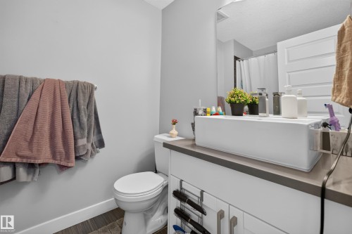 Bathroom vanity with a rectangular vessel sink, gray countertop, and white cabinetry featuring brushed nickel hardware - 706 5151 Windermere Boulevard, Edmonton, AB 