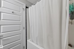 White paneled interior door with chrome hardware, featuring a full bathtub with a shower curtain - 