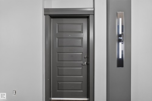 Panel-style entry door with modern hardware - 706 5151 Windermere Boulevard, Edmonton, AB 