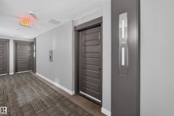Corridor featuring light gray walls, dark wood-finish doors, and patterned carpet flooring - 
