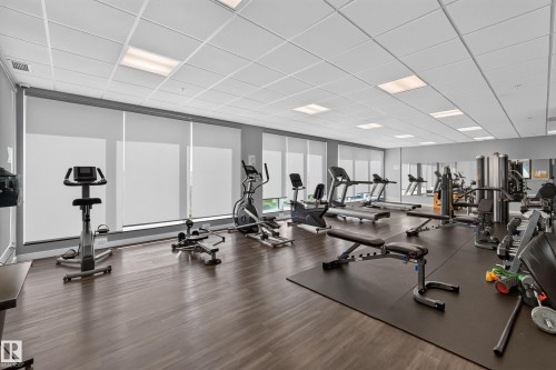 Fitness center with wood-finish flooring, ample natural light from multiple windows, and extensive mirrored walls - 706 5151 Windermere Boulevard, Edmonton, AB 