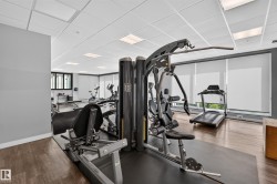 Fitness center with wood-finish flooring, drop ceiling with integrated lighting, and multiple exercise machines - 