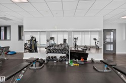 Fitness center featuring a mirrored wall, rubber flooring, and track lighting - 
