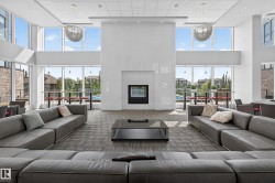 Spacious communal room featuring a floor-to-ceiling window wall, a central fireplace, recessed lighting, and modern pendant light fixtures - 