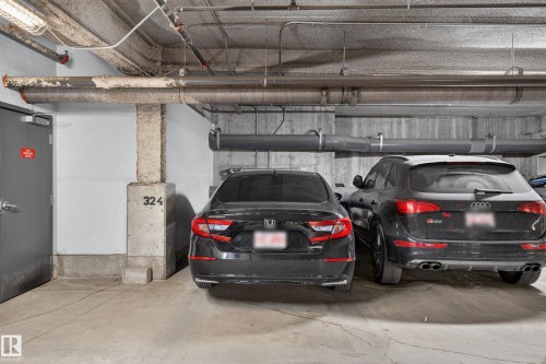 Concrete parking garage with exposed ceiling pipes and concrete support pillars - 706 5151 Windermere Boulevard, Edmonton, AB 