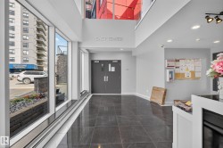 Spacious lobby featuring polished dark tile flooring, a high ceiling, and full-height windows - 