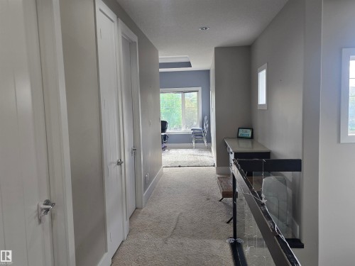 Hallway with light gray walls, white trim, and a textured carpet - 1019 175 Street, Edmonton, AB 