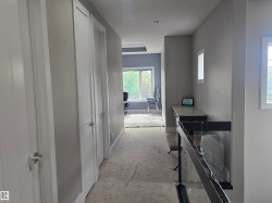 Hallway with light gray walls, white trim, and a textured carpet - 
