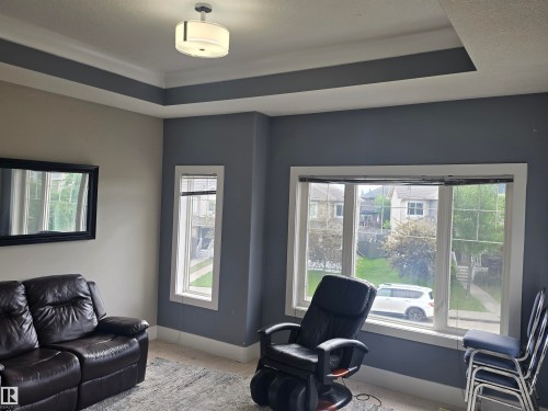 Tray ceiling design with recessed lighting, large pane windows with white trim, and light-colored wall-to-wall carpeting - 1019 175 Street, Edmonton, AB 