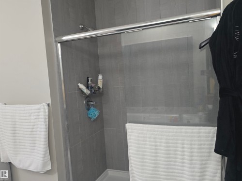 Walk-in shower featuring gray subway tile walls, a chrome showerhead, and a clear glass sliding door - 1019 175 Street, Edmonton, AB 