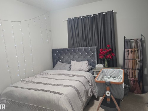Bedroom featuring light gray walls, dark gray window treatments, and a tufted gray headboard - 1019 175 Street, Edmonton, AB 