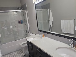 Bathroom featuring a dual vanity with light-toned countertops, undermount sinks, and chrome faucets - 