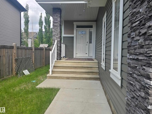 Front entrance with stacked stone accent pillar, durable siding exterior, and a concrete pathway leading to stepped porch entry - 1019 175 Street, Edmonton, AB 