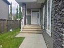 Front entrance with stacked stone accent pillar, durable siding exterior, and a concrete pathway leading to stepped porch entry - 1019 175 Street, Edmonton, AB 