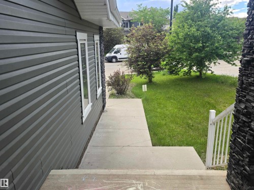 Exterior featuring horizontal siding, white trim windows, concrete steps, and a stone facade element - 1019 175 Street, Edmonton, AB 
