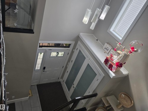 Entryway featuring a white paneled door with decorative glass inserts, a transom window, and a sidelight - 1019 175 Street, Edmonton, AB 