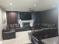 Living area featuring a fireplace with a white mantel and stone surround, recessed lighting, and a ceiling fan - 