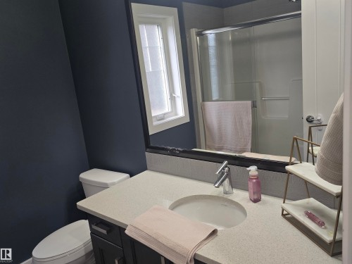 Bathroom featuring a light-colored countertop with an undermount sink, a chrome faucet, and dark cabinetry - 1019 175 Street, Edmonton, AB 