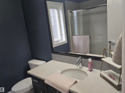 Bathroom featuring a light-colored countertop with an undermount sink, a chrome faucet, and dark cabinetry - 