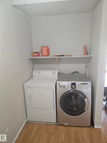 Dedicated laundry area featuring a built-in shelf, wood-finish flooring, and light-toned walls - 10838 108 Street Nw, Edmonton, AB 