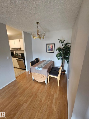 Dining area featuring wood-finish flooring, a brass-tone chandelier with globe lights, and a neutral color palette - 10838 108 Street Nw, Edmonton, AB 