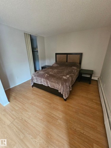 Spacious room featuring wood-finish flooring, light-colored walls, and a convenient closet with bi-fold doors - 10838 108 Street Nw, Edmonton, AB 