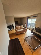 Open-concept living area featuring wood-finish flooring, a dedicated desk area, and a sliding glass door providing access to a private balcony - 