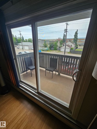 Sliding glass patio door opening to a private balcony featuring a concrete floor and dark wood-finish railing - 10838 108 Street Nw, Edmonton, AB 