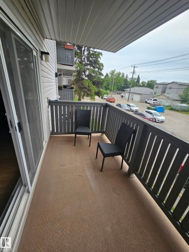 Outdoor balcony featuring a textured floor, gray slatted railings, and a white vinyl-sided exterior - 10838 108 Street Nw, Edmonton, AB 