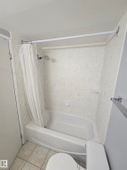 Bathroom featuring a white bathtub, ceramic tile flooring, and a shower with a handheld fixture - 
