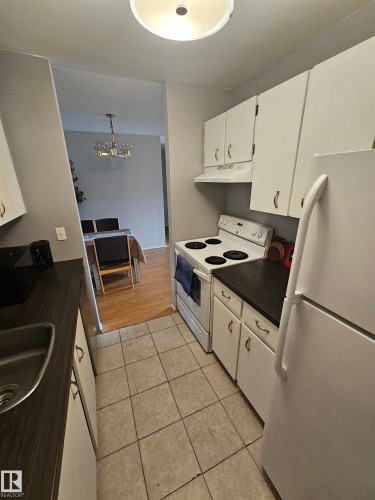 Kitchen featuring white cabinetry, dark countertops, a built-in range, and tile flooring - 10838 108 Street Nw, Edmonton, AB 