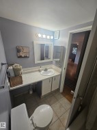 Compact bathroom featuring a white vanity with integrated sink, a built-in medicine cabinet, ceramic tile flooring, and a towel bar - 