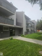 Multi-story building featuring gray horizontal siding and individual balconies with dark gray railings - 