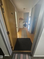 Entryway with wood-finish flooring, featuring a built-in laundry area with shelving - 