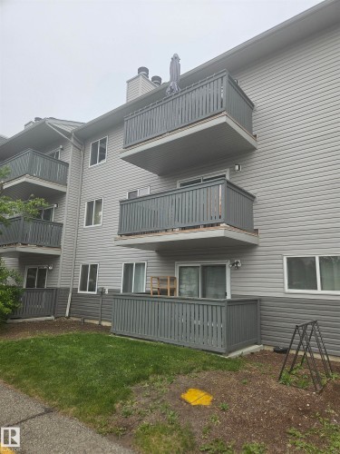Multi-level residential building featuring gray horizontal siding and individual balconies on upper floors - #206 10838 108 Street Nw, Edmonton, AB - Outdoor With Balcony
