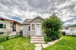 Gray siding exterior with a white entry door, framed by a concrete stoop and stepping stones - 