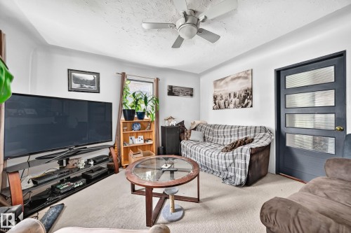 Living area featuring neutral wall tones, textured ceiling, and carpet flooring - 11939 89 Street, Edmonton, AB 