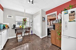 Kitchen area featuring dark tile flooring, white cabinetry, track lighting, and a window with blinds - 