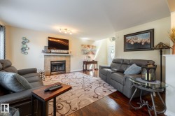 Living area featuring wood-finish flooring, a fireplace with a stone-tile surround, and a mantel - 
