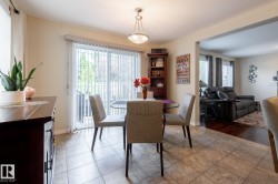 Dining area featuring neutral-toned tile flooring and a glass patio door with vertical blinds - 