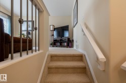 Carpeted staircase with white handrail and wrought iron balusters - 