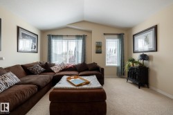 Spacious living area featuring neutral-toned walls, vaulted ceilings, and soft carpeting - 