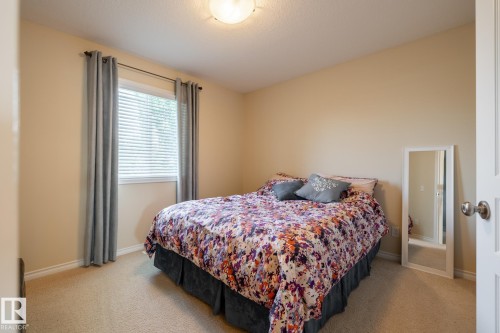 Carpeted room featuring a window with blinds and drapes, light beige walls, and a white ceiling - 5820 7 Avenue Sw, Edmonton, AB - Indoor Photo Showing Bedroom