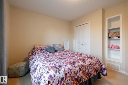 Bedroom featuring neutral wall paint, carpet flooring, a bifold closet door, and built-in shelving - 5820 7 Avenue Sw, Edmonton, AB - Indoor Photo Showing Bedroom