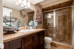 Bathroom featuring a glass-enclosed shower, a vanity with a countertop, an undermount sink, a chrome faucet, and a wall-mounted light fixture - 