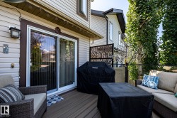 Expansive outdoor deck featuring wood-finish flooring, sliding glass door access, decorative privacy screen, and mature perimeter trees - 