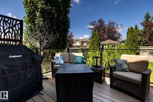 Spacious outdoor deck featuring composite decking, glass panel railings, and a decorative privacy screen - 5820 7 Avenue Sw, Edmonton, AB - Outdoor With Deck Patio Veranda